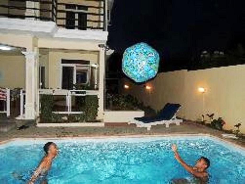 two men swimming in a swimming pool at night at 2 bedrooms appartement at Grand Baie 400 m away from the beach with shared pool enclosed garden and wifi in Grand-Baie