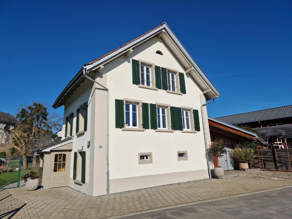 Una casa blanca con persianas verdes. en Ferienhaus Kluser en Oberriet