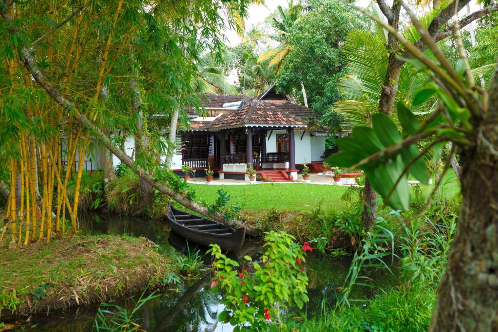 a house with a boat in the middle of a river at Vembanad House Boutique Back Water Retreat in Alleppey