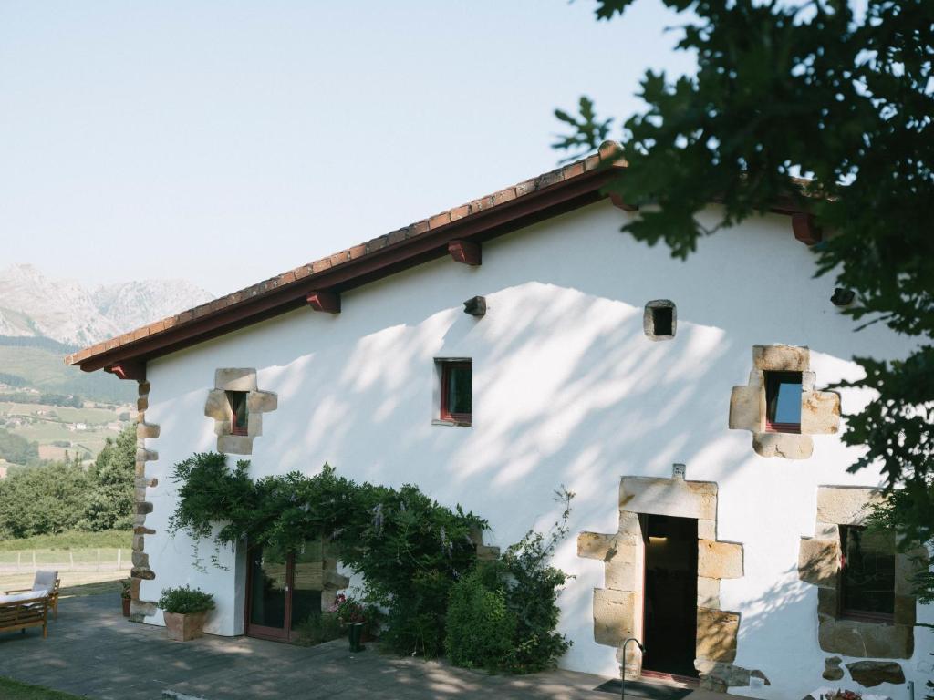 a white building with windows and vines on it at Casa Goikomaia in Arrázola