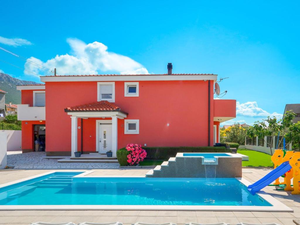 een rood huis met een zwembad voor een huis bij Holiday Home QUEEN AHN - SPY250 by Interhome in Kaštela