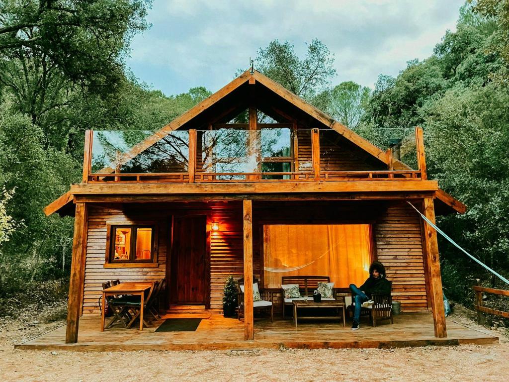 une femme assise devant une cabane en rondins dans l'établissement CABAÑAS DEL BOSQUE CERCA DE CORDOBA, à Cordoue