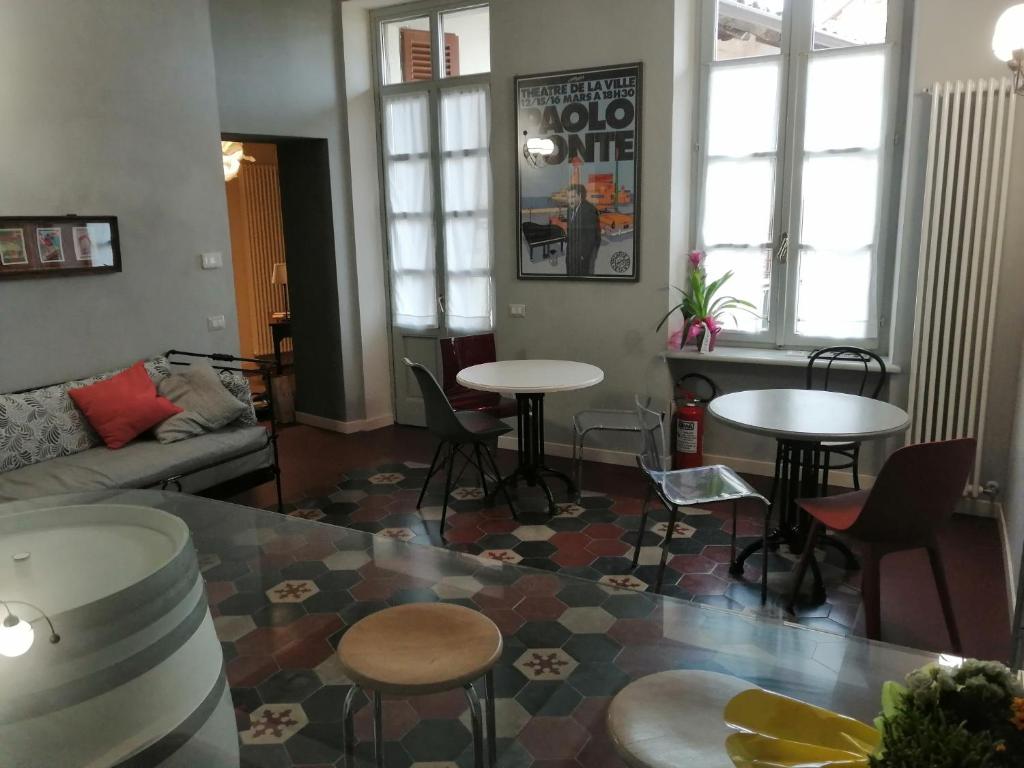 sala de estar con mesas, sillas y sofá en L' estate di san Martino Room Rental - free park, en Asti
