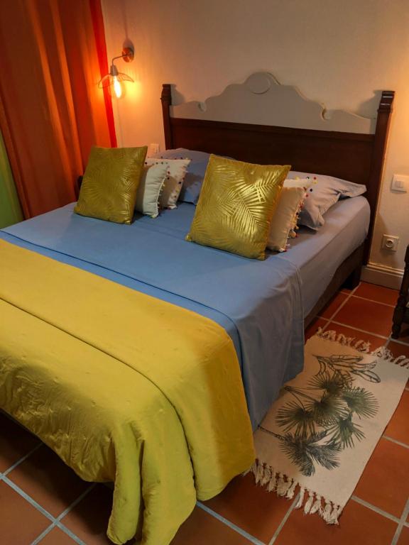 a bedroom with a bed with yellow sheets and pillows at Colibri des Rochers.Vue mer &amp; piscine.Anse des Rochers in Saint-François