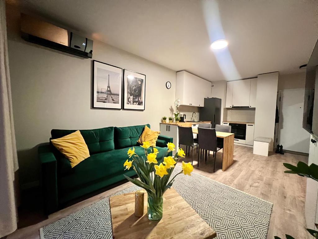 salon z zieloną kanapą i stołem z żółtymi kwiatami w obiekcie Apartamenty Milionowa z garażem i klimatyzacją w Łodzi