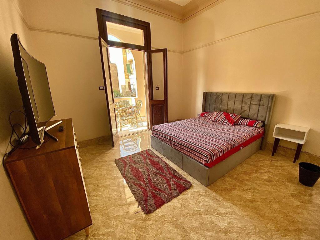 a bedroom with a bed and a flat screen tv at Comfy private room with big sunny balcony near cairo airport مكان مودرن للاقامة دقائق من مطار القاهرة الدولى in Cairo
