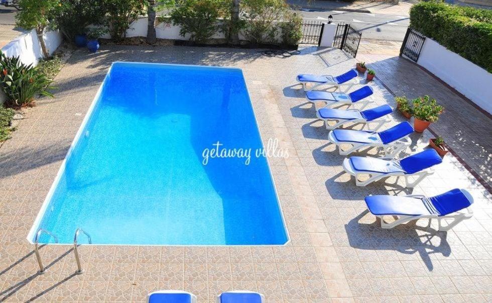 a group of chairs and a swimming pool with a row of chairs and a group at LULA VILLA in Ayia Napa