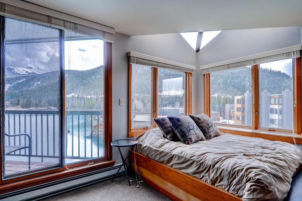 a bedroom with a bed and large windows with mountains at Lakeside 1491 in Keystone