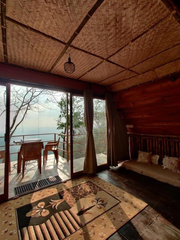 Zimmer mit einem Bett, einem Tisch und Fenstern in der Unterkunft Sunset Valley Kerala - Where Every Evening Unveils a Perfect Sunset with Private Waterfalls in Pīrmed