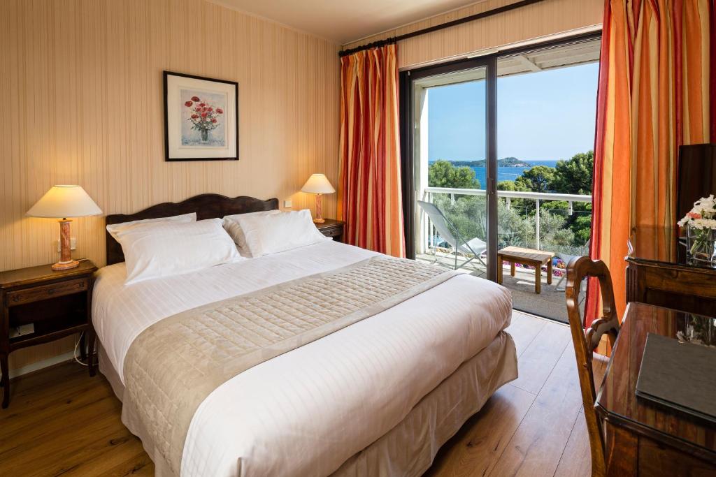 a bedroom with a large bed and a large window at Hotel Provençal in Hyères