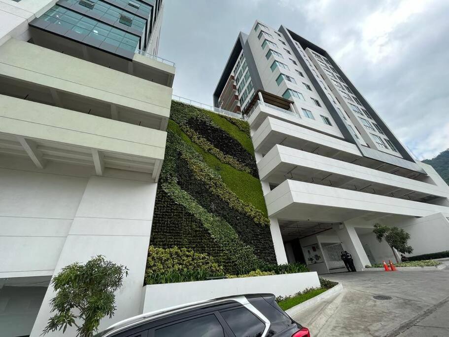 a car parked in front of a building with a green wall at New luxury apartment with king - size bed Ceibos in Guayaquil