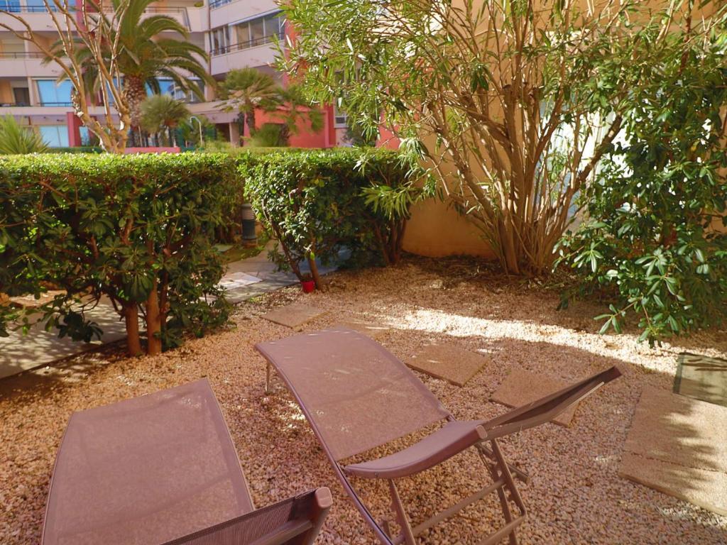 2 chaises et une table dans un jardin avec un bâtiment dans l'établissement Appartement RDC à Sète: 3 pièces, Piscine, Accès Plage, Parking, Wifi - FR-1-472A-167, à Sète
