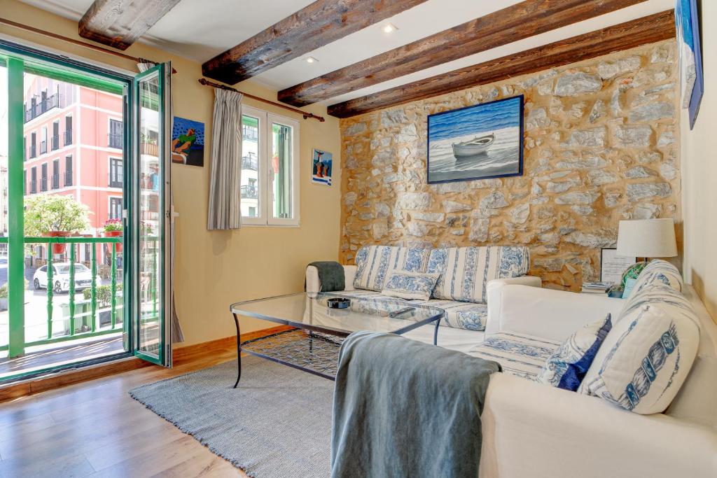 a living room with a couch and a stone wall at Maravilloso apartamento en el corazón de Hondarribia in Hondarribia