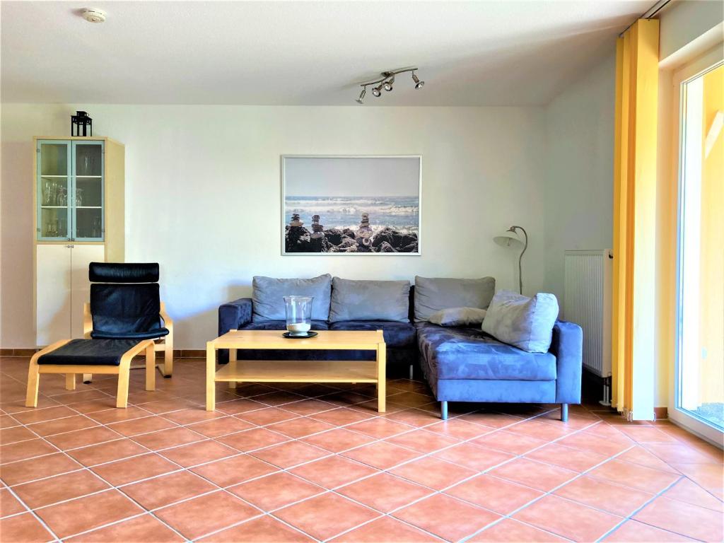 ein Wohnzimmer mit einem blauen Sofa und 2 Stühlen in der Unterkunft Usedom Ferienwohnungen Riwa ruhig in Ostseebad Kölpinsee