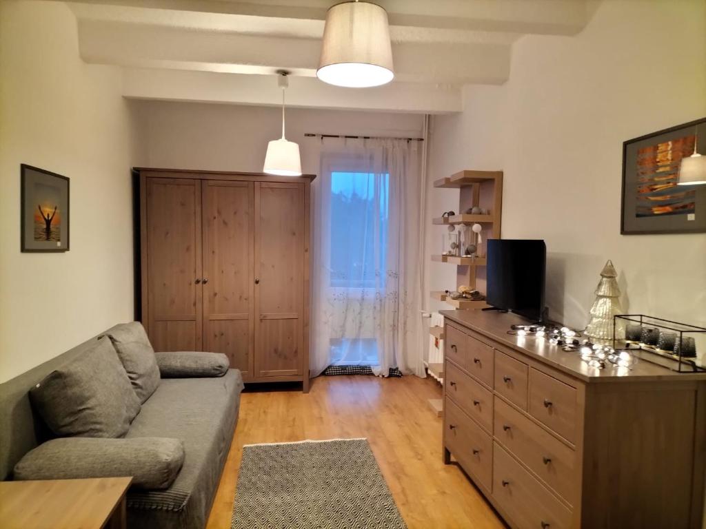 a living room with a couch and a dresser with a television at Stacja Kocham Morze in Gdańsk