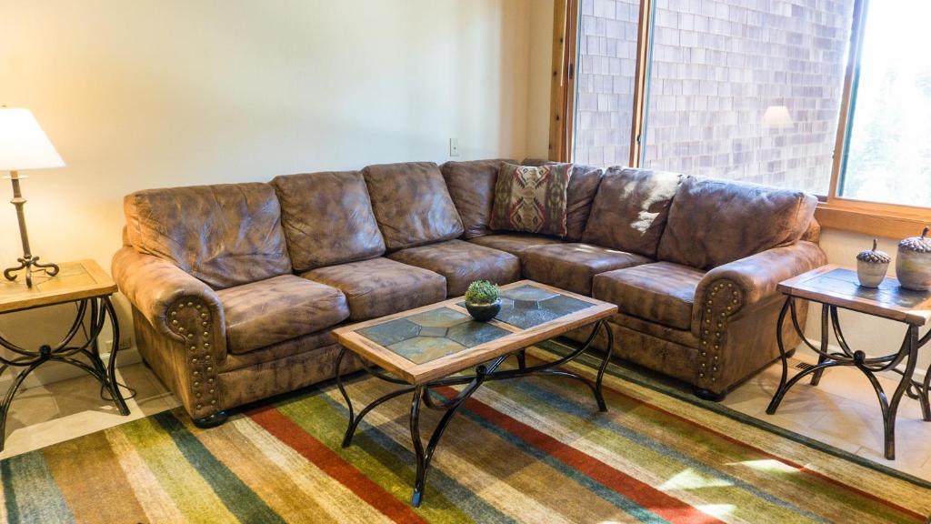 um sofá de couro castanho numa sala de estar com duas mesas em Ski Trails 4024 em Truckee