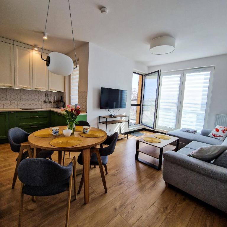 a kitchen and a living room with a table and a couch at Piękny Puck Apartamenty z tarasami in Puck