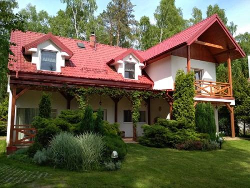 une maison avec un toit rouge sur une cour dans l'établissement U Kasi, à Dębki
