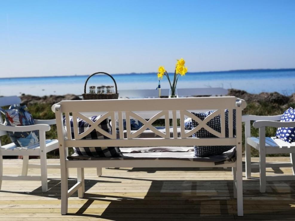 a white bench with a table and flowers on the beach at Sjöstugor med SPA i Höllviken in Höllviken