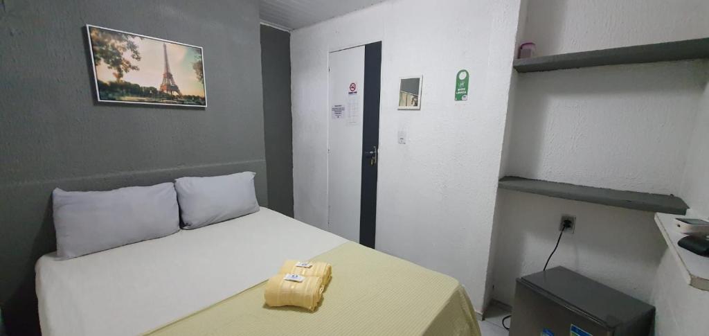 um pequeno quarto com uma cama branca e uma mesa amarela em Casa Aeroporto Pousada em Recife