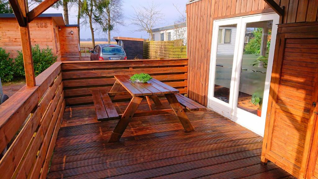 una terrazza in legno con un tavolo in legno e una pianta di *Little Oak* Super schattige houten chalet met veranda in een bosrijke omgeving. a Eext
