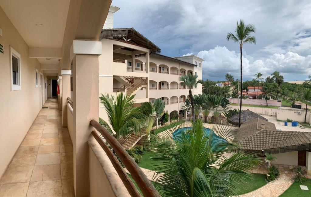 einen Balkon mit Blick auf ein Hotel mit Pool und Palmen in der Unterkunft Apartment Cumbuco Residence in Cumbuco