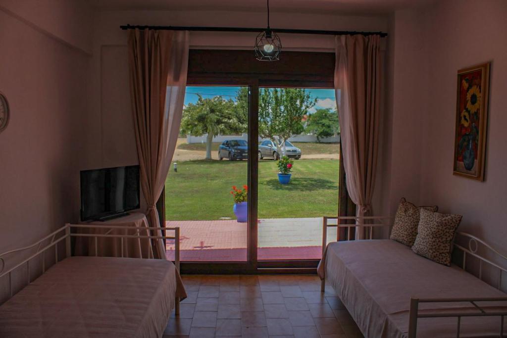 a bedroom with two beds and a sliding glass door at Lucid Dream Apt. Bozinis 2 in Psakoudia