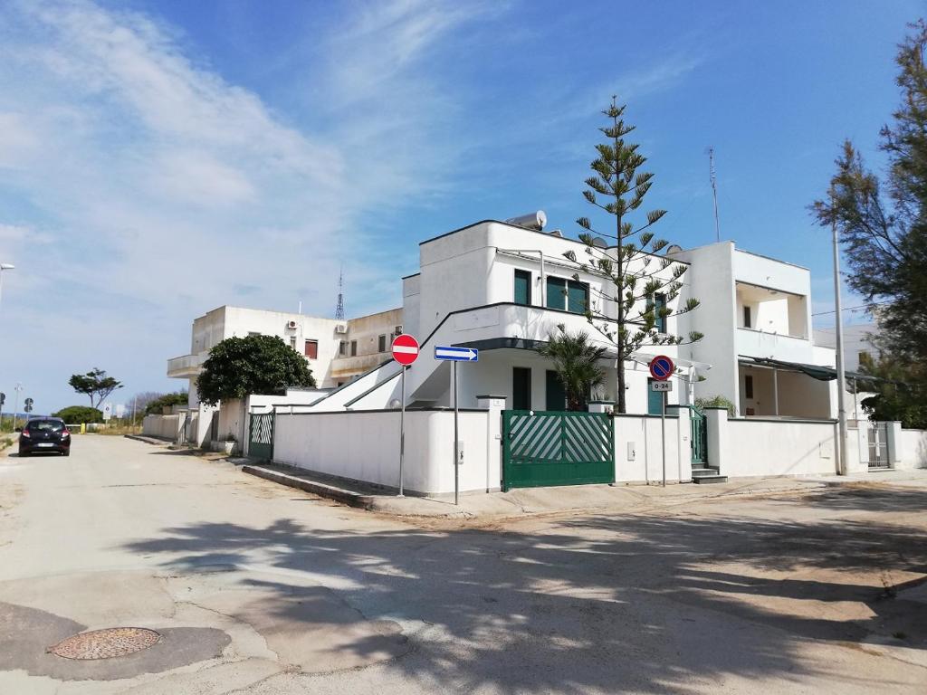 un edificio blanco con una valla frente a una calle en 059 e 060 Spiaggia di SalentoinVacanza.Com, en Torre Pali