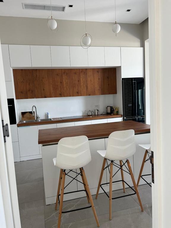 una cocina con armarios blancos y taburetes blancos en Family villa, en Baku
