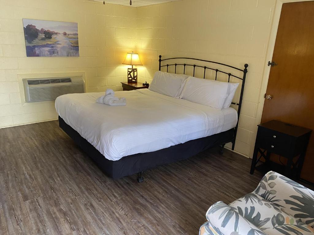 a bedroom with a large white bed and a chair at JI1, King Guest Room at the Joplin Inn at entrance to the resort Hotel Room in Mount Ida