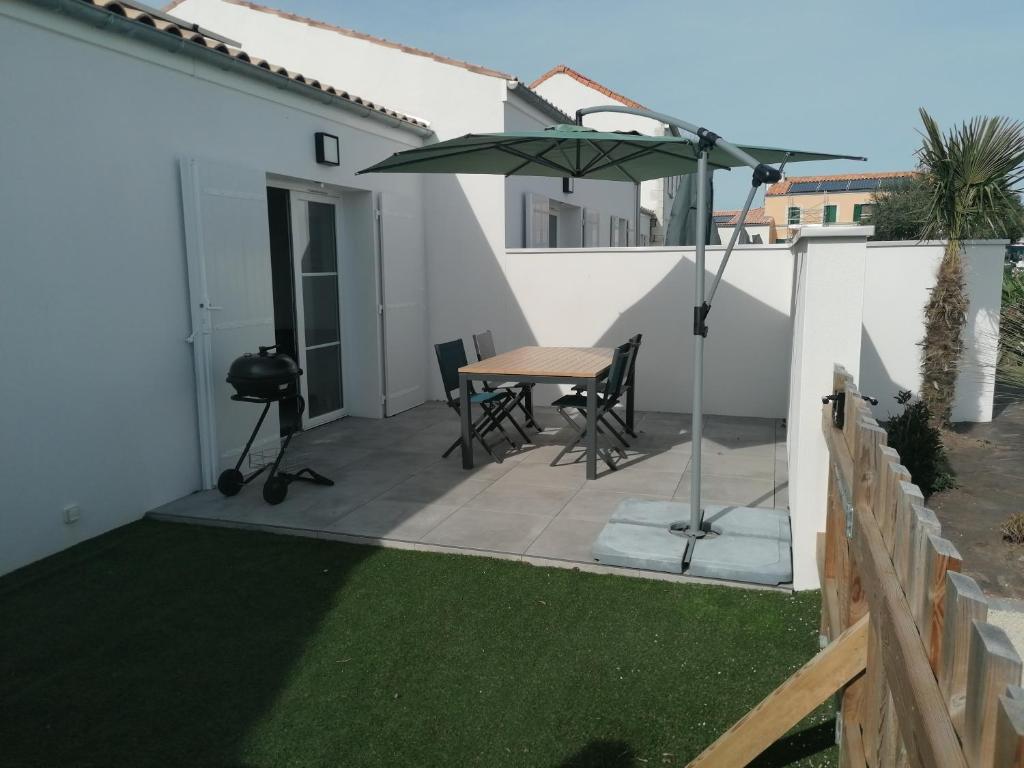 a patio with a table and an umbrella at LA FREGATE Maison avec piscine/parking/wifi/plages 5kms in Les Mathes