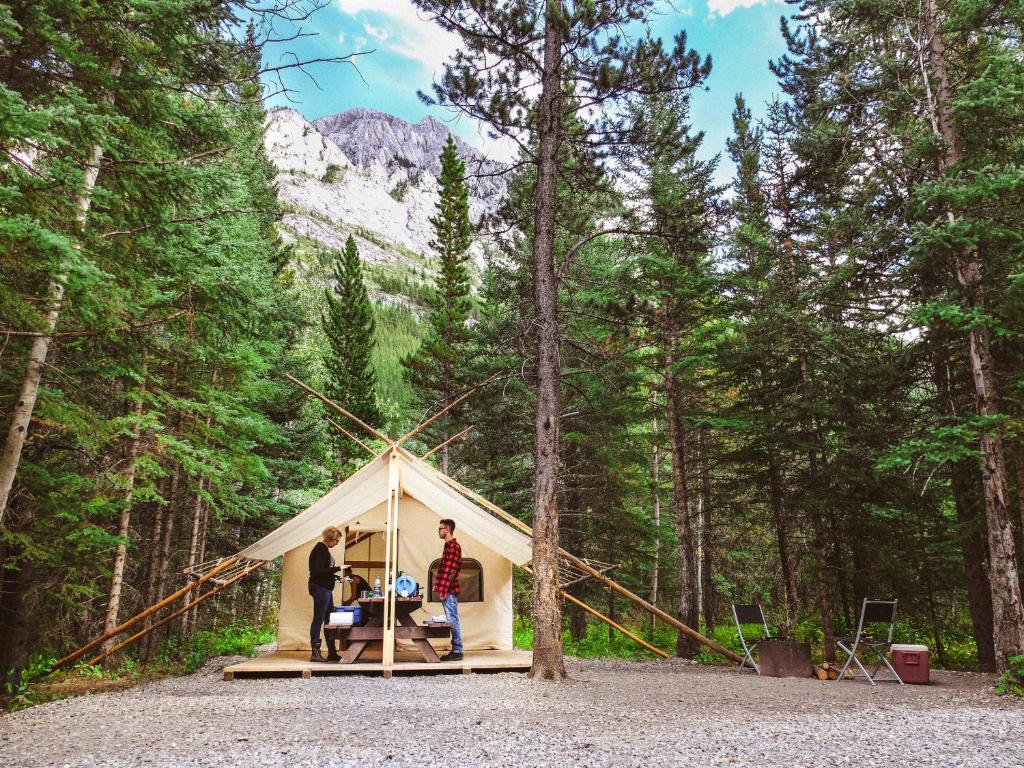 two people standing in front of a tent in the woods at Sundance By Basecamp in Kananaskis Village
