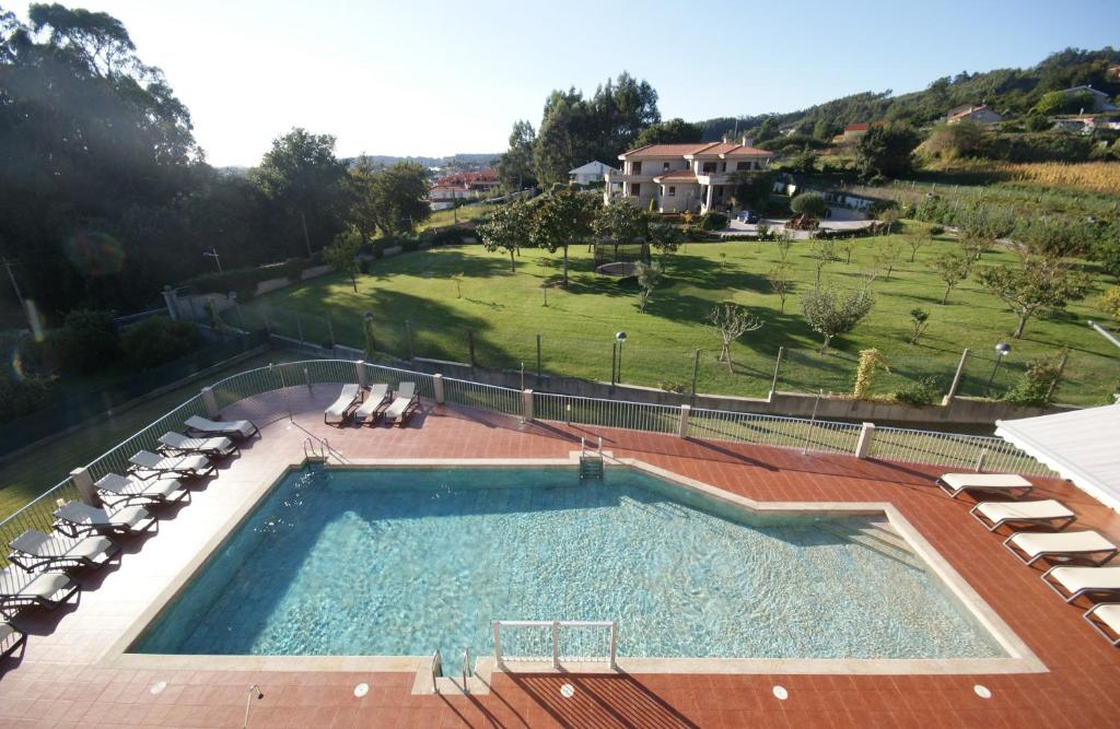 uma grande piscina com espreguiçadeiras e um campo em Apartamentos Mirador de Reis em Sanxenxo