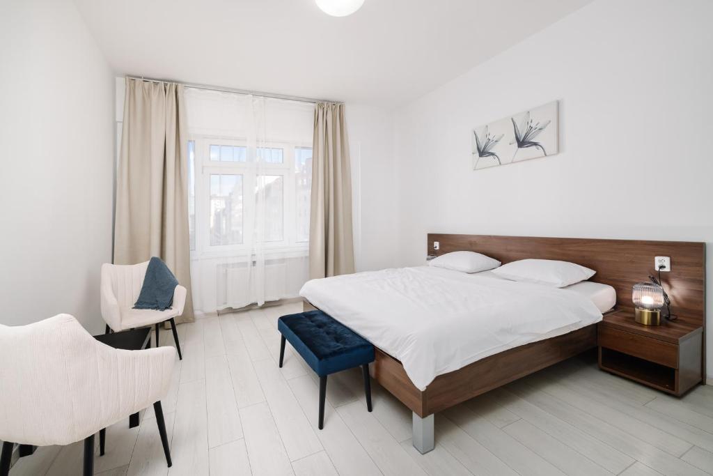 1 dormitorio con 1 cama grande y 1 silla azul en Self check-in apartments by Amber, en Bratislava