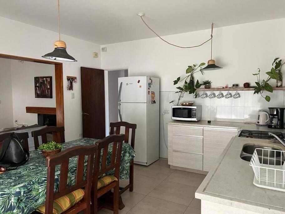 a kitchen with a table and a white refrigerator at Alquiler de casa zona Cerro in Córdoba