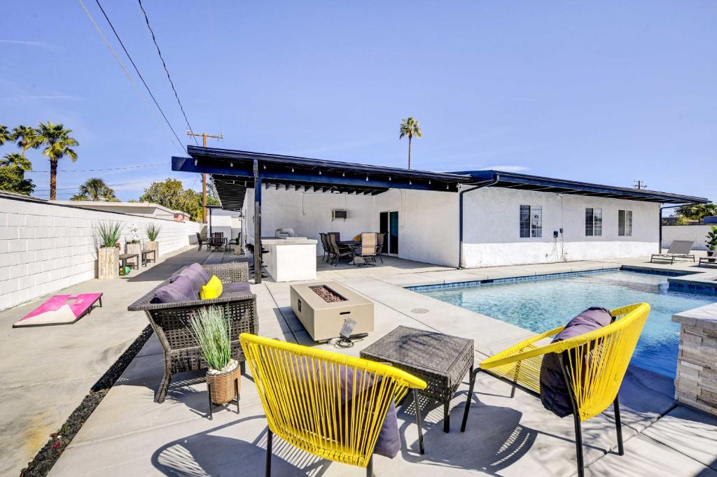 a patio with yellow chairs and a swimming pool at Stylish Palm Springs Home with Outdoor Oasis! in Palm Springs