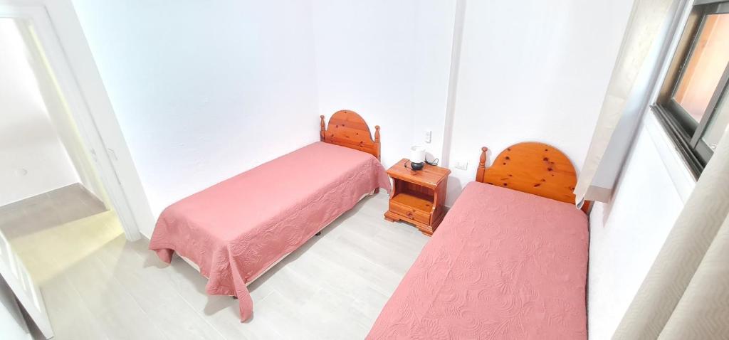 2 camas en una habitación pequeña con sábanas rosas en La colina en Arona
