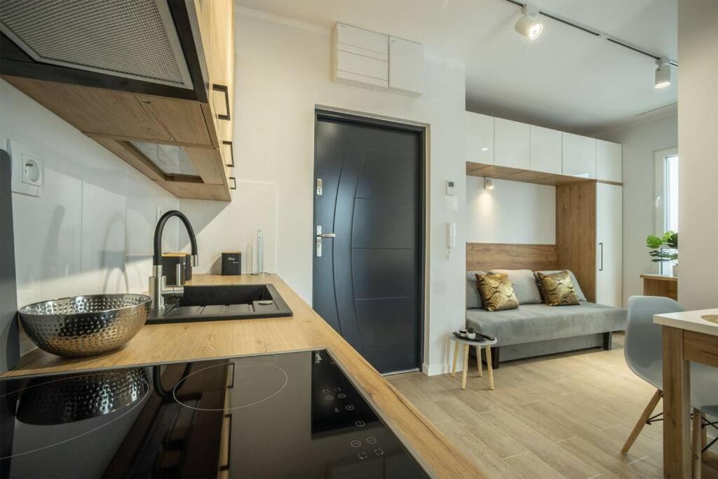 a kitchen with a sink and a living room with a couch at WiguryTower Apartaments 62' in Łódź