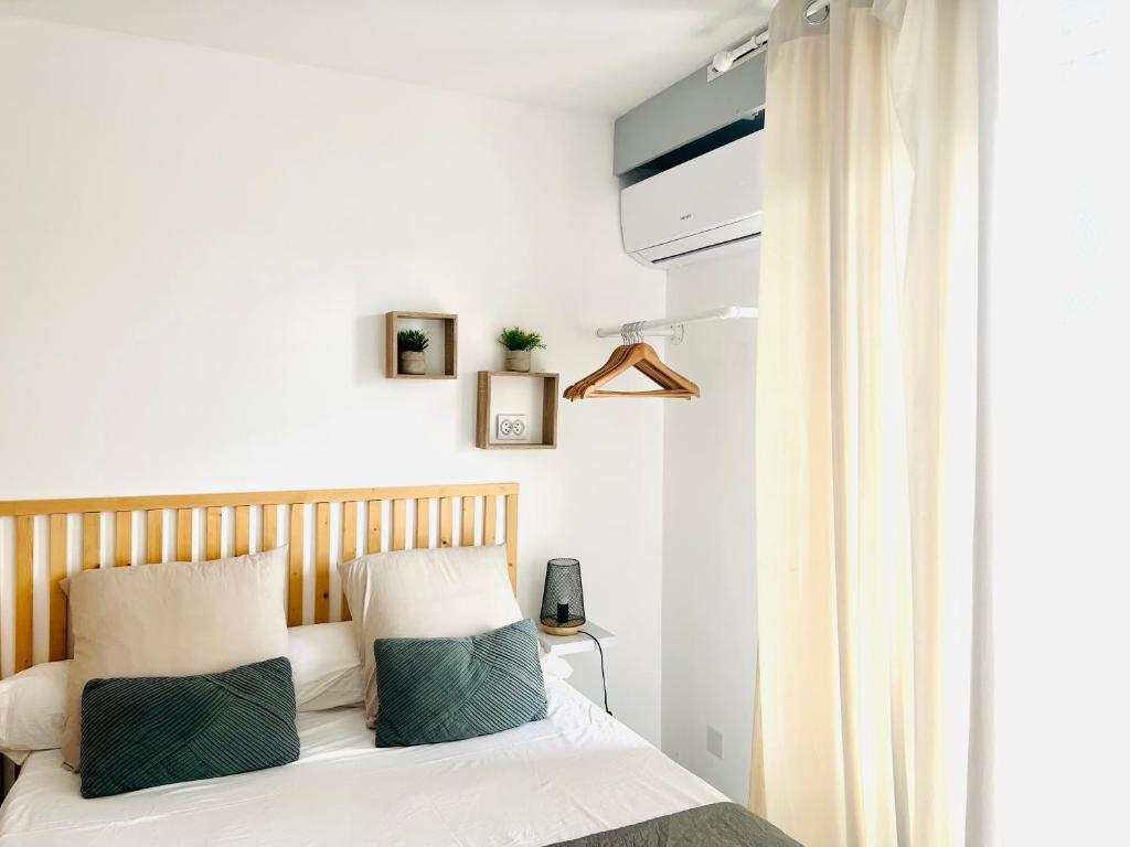a bedroom with a bed with white sheets and green pillows at LES PALMIERS - Appartement avec piscine proche plage in Antibes