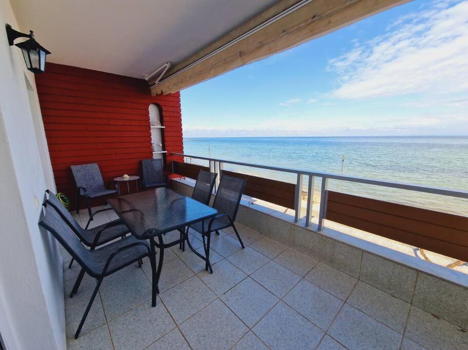 a balcony with a table and chairs and the ocean at Viktoria Sea View Apartment in Perea