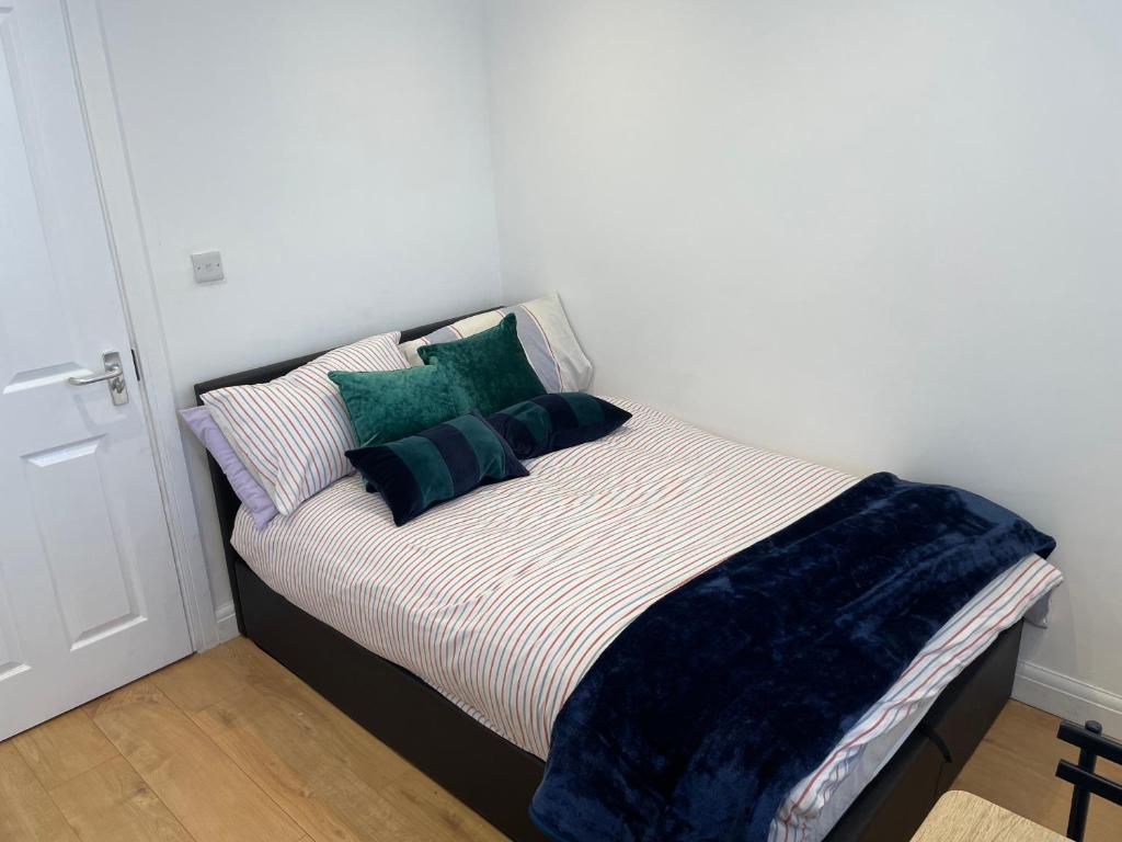 a bed with green pillows on it in a room at Double Room with shared bathroom in private self-contained flat you will share with one other person in family house 2 minutes walk from Tufnell Park tube station 15 minutes walk from Camden Town in London