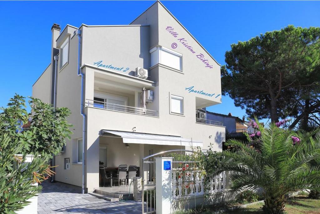 ein weißes Haus mit einem Zaun davor in der Unterkunft Apartments Villa Kristina in Bibinje