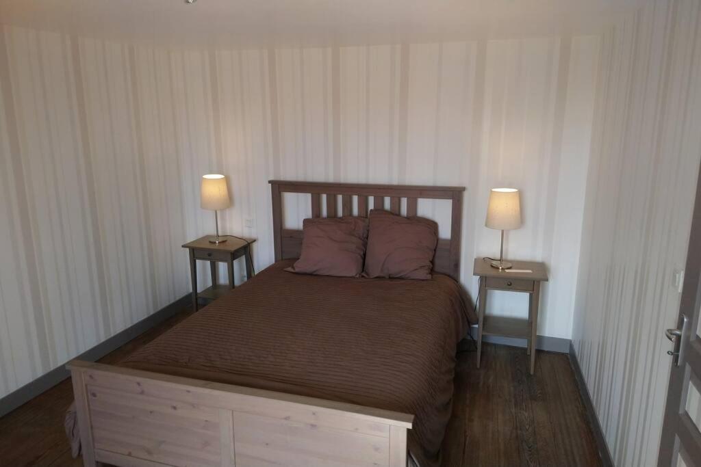 a bedroom with a bed with two lamps on both sides at Logement avec deux chambres dans maison de village 