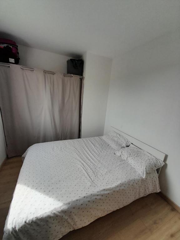 een slaapkamer met een bed met een wit dekbed bij Le Laurier Rose in Le Pallet