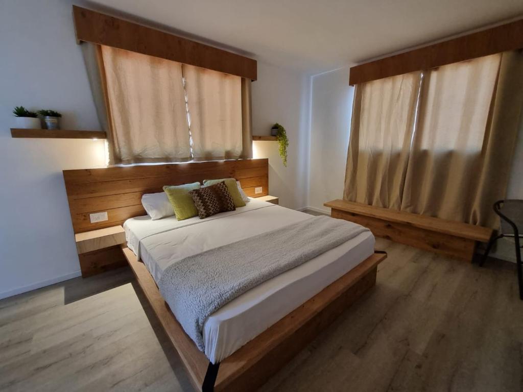 a bedroom with a large bed and two windows at מלון טיבריא in Tiberias