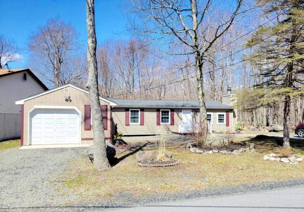 a house with a white garage and a tree at The Family Getaway in Tobyhanna
