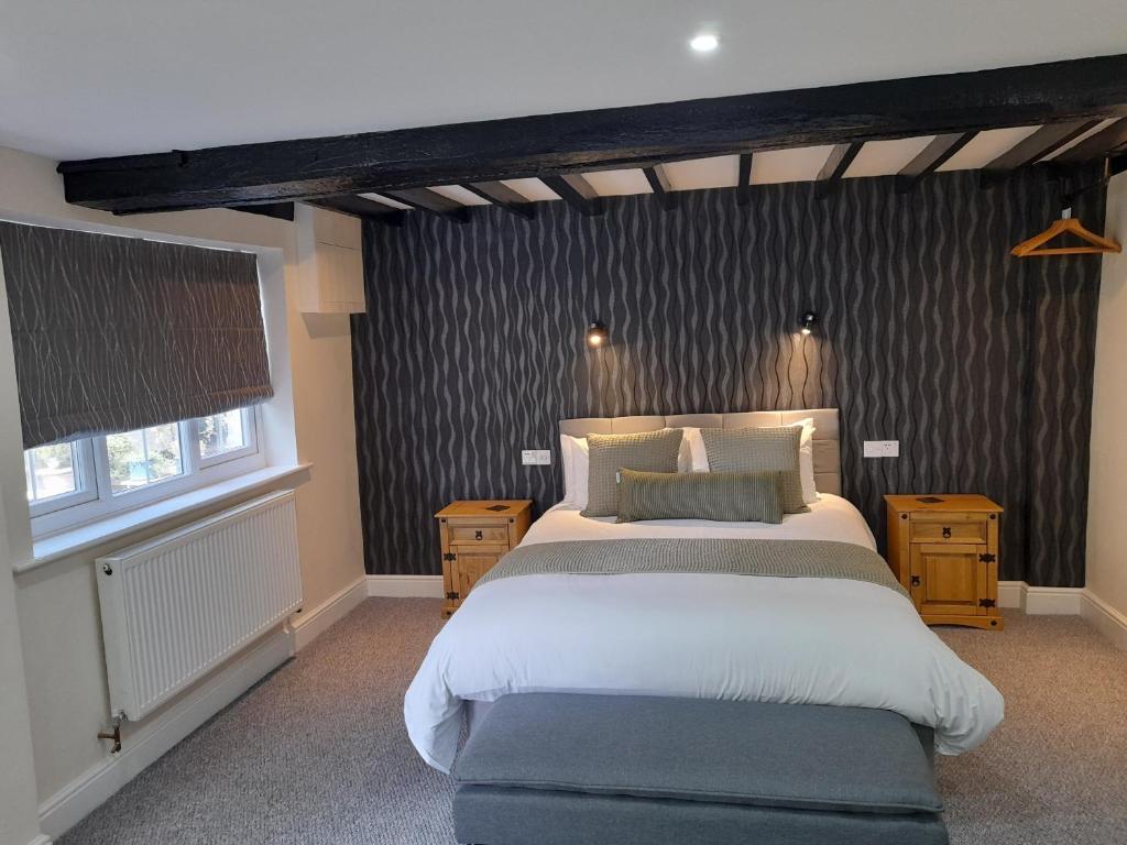 a bedroom with a large bed and two windows at The George & Dragon Hotel in Long Melford