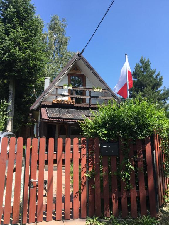 a house with a red fence and a flag at Domek Jakusówka Laliki Pochodzita w sercu Beskidów in Laliki