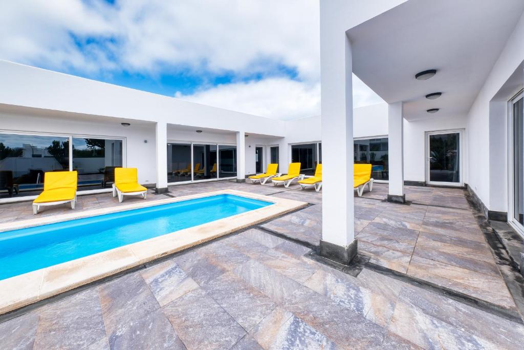 Villa con piscina y sillas amarillas en Casa Eden naturist area, full privacy, relax and private pool en Charco del Palo