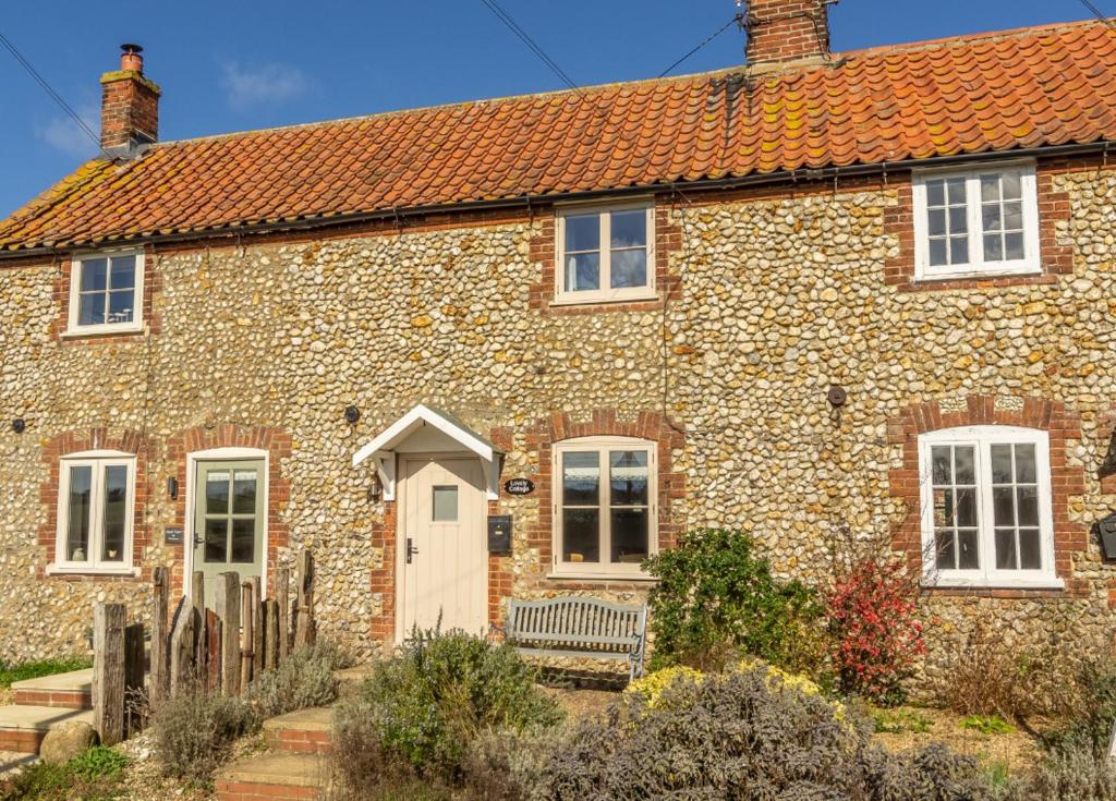 a large stone house with a red roof at Lovely Cottage in North Creake